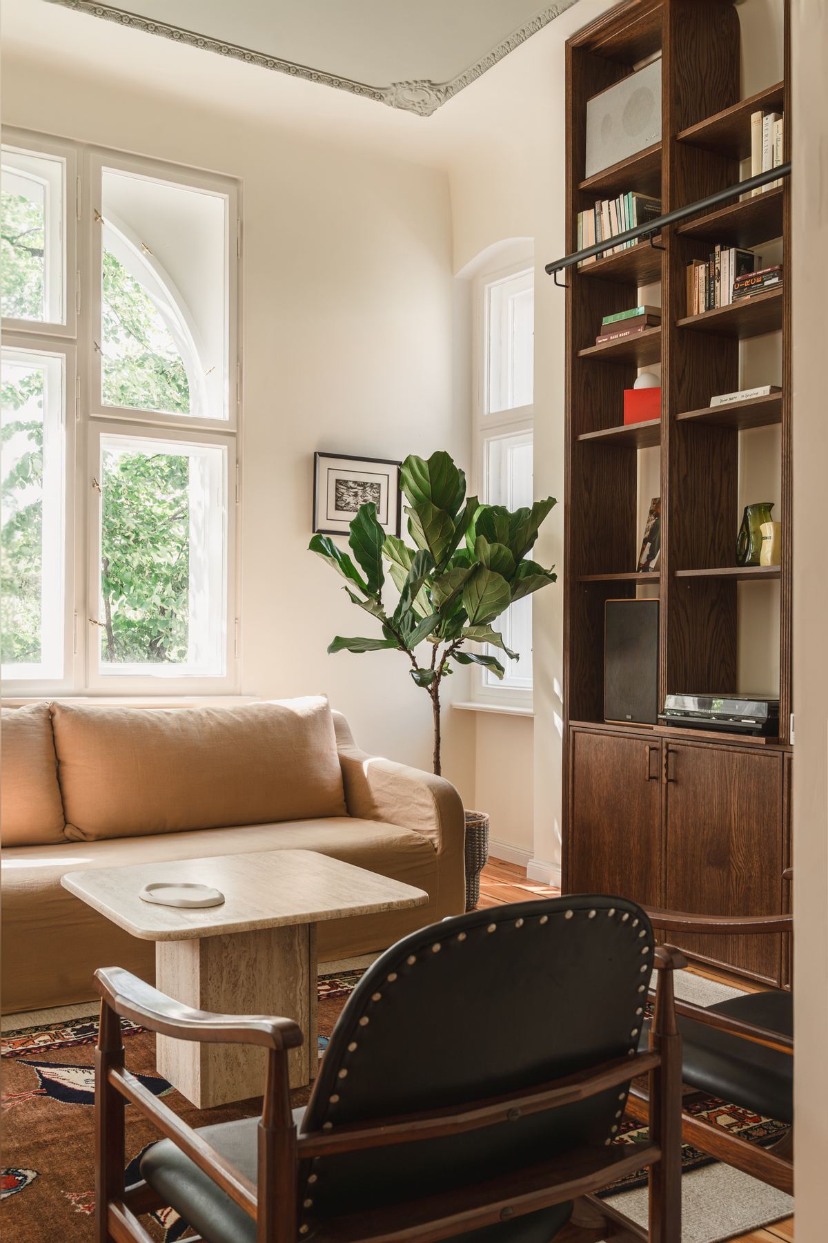 Two black leather armchairs facing a stone coffee table, with the bookshelves on one side and an arched window on the other.