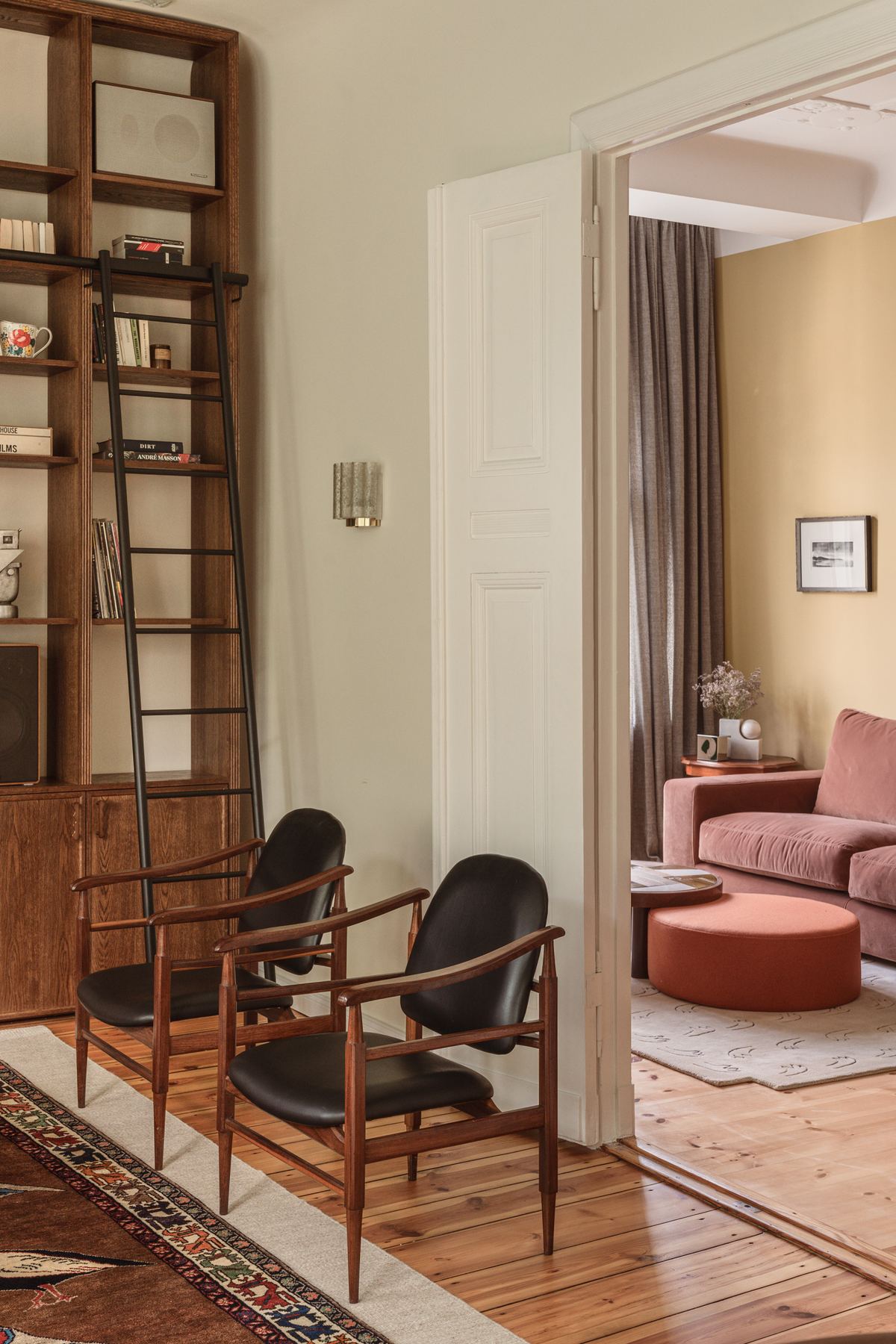 Looking from the living room through an open double door into the study, where a pink velvet sofa is visible.